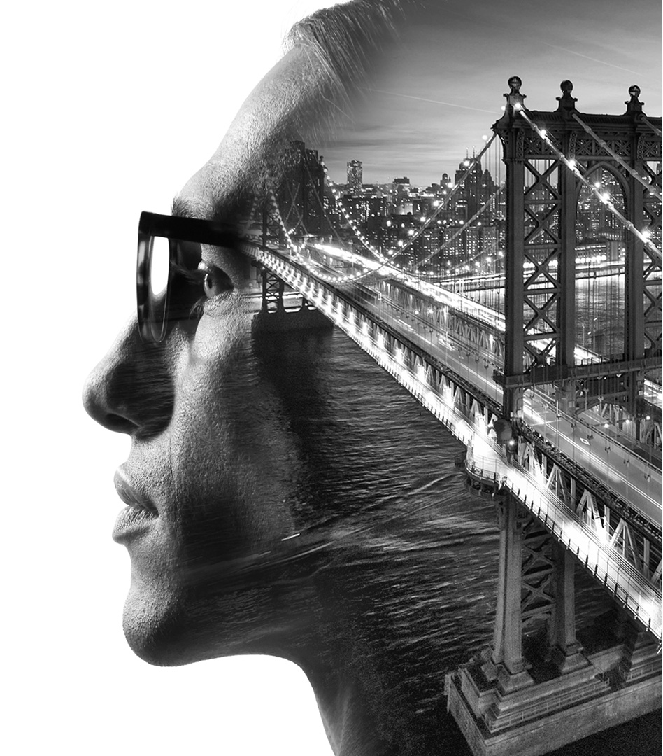 Double exposure profile portrait of a man wearing glasses, featuring a nighttime view of a bridge and city lights layered within his silhouette.